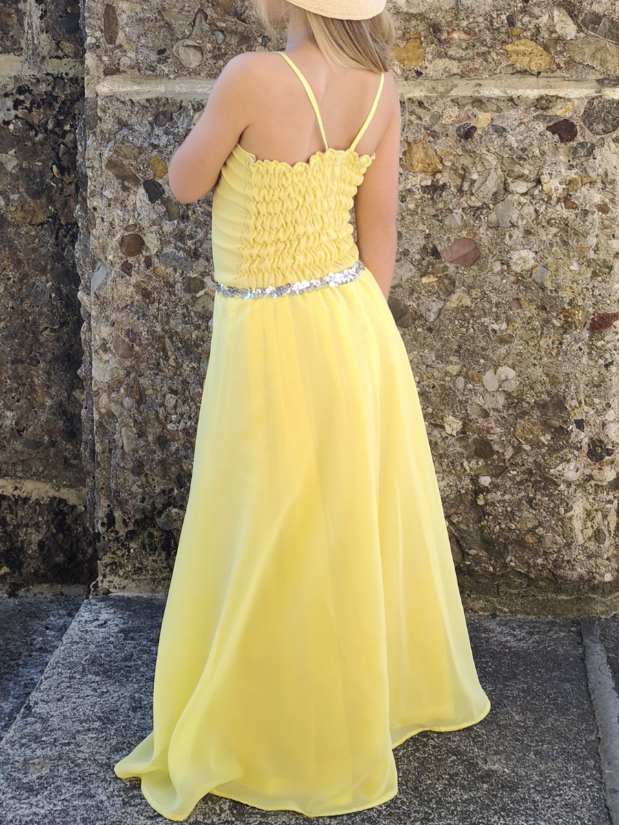 Mädchen in gelbem Chiffonkleid mit Pailletten von hinten